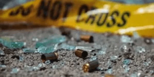 Bullet casings are scattered on the ground near a glass.