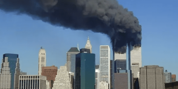 A black smoke billows from the top of a building.