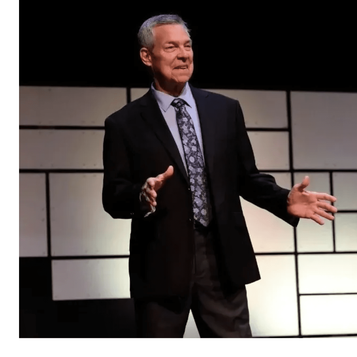 A man in suit and tie standing on stage.